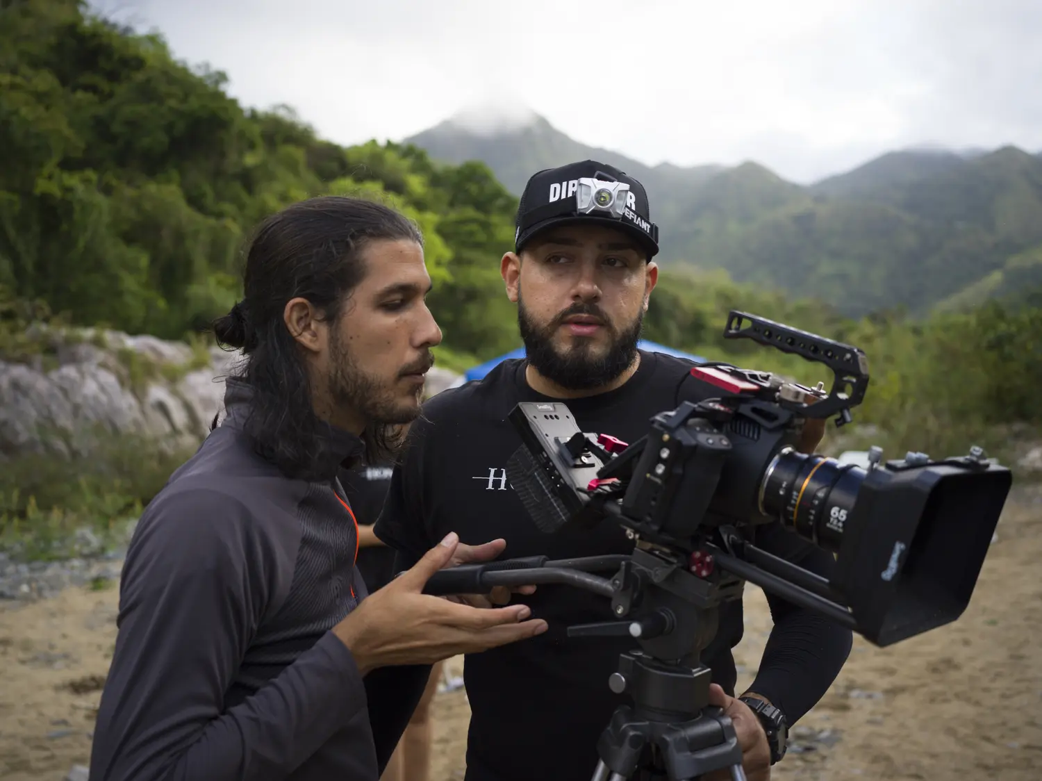 Director and camera operator conferring, green mountains behind