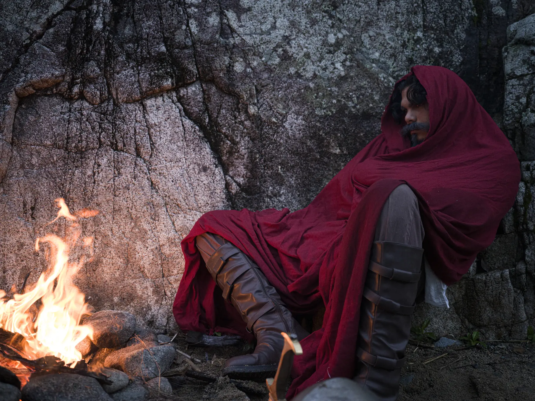 Poster frame: a cloaked figure beside open flame